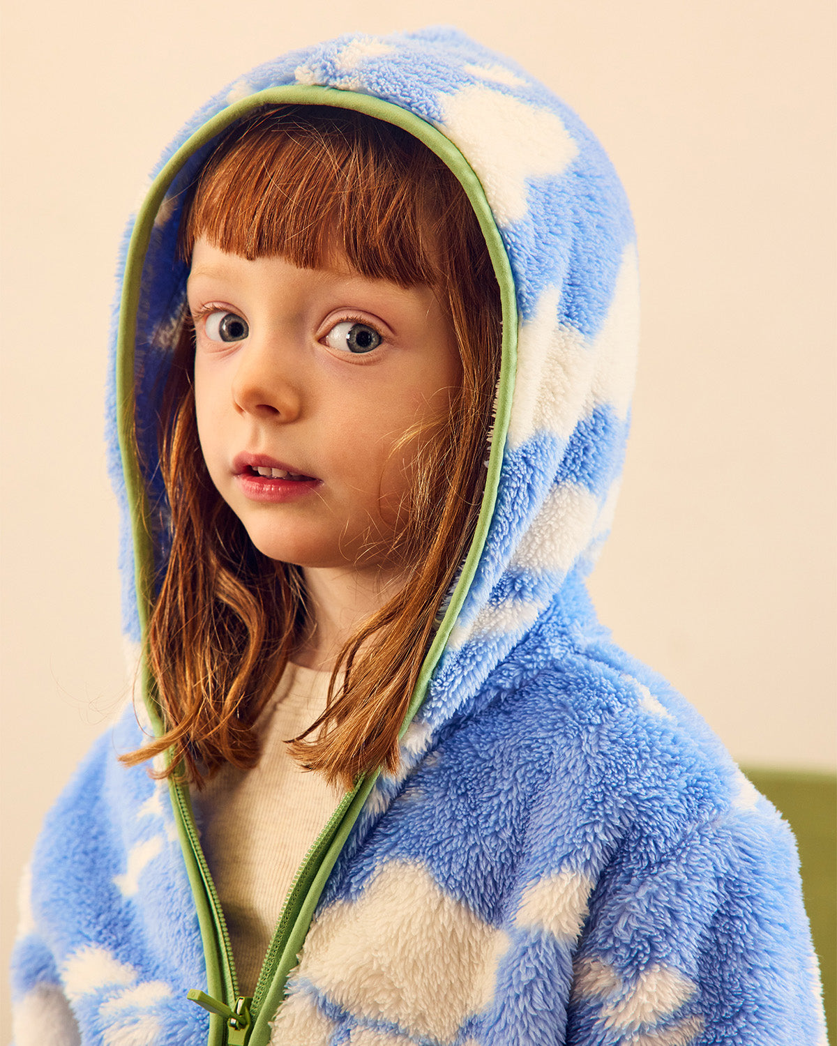 blue and white fleece with green trim on red head girl looking at camera