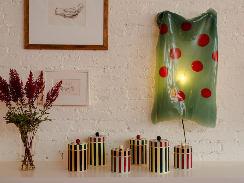 Canisters lined up with lamp and flowers in front of a brick wall