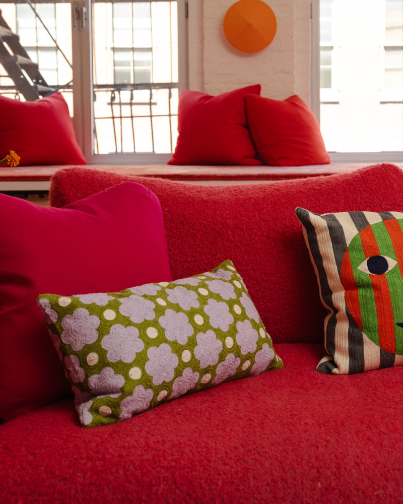 Red sofa with Raspberry bolster pillow on it