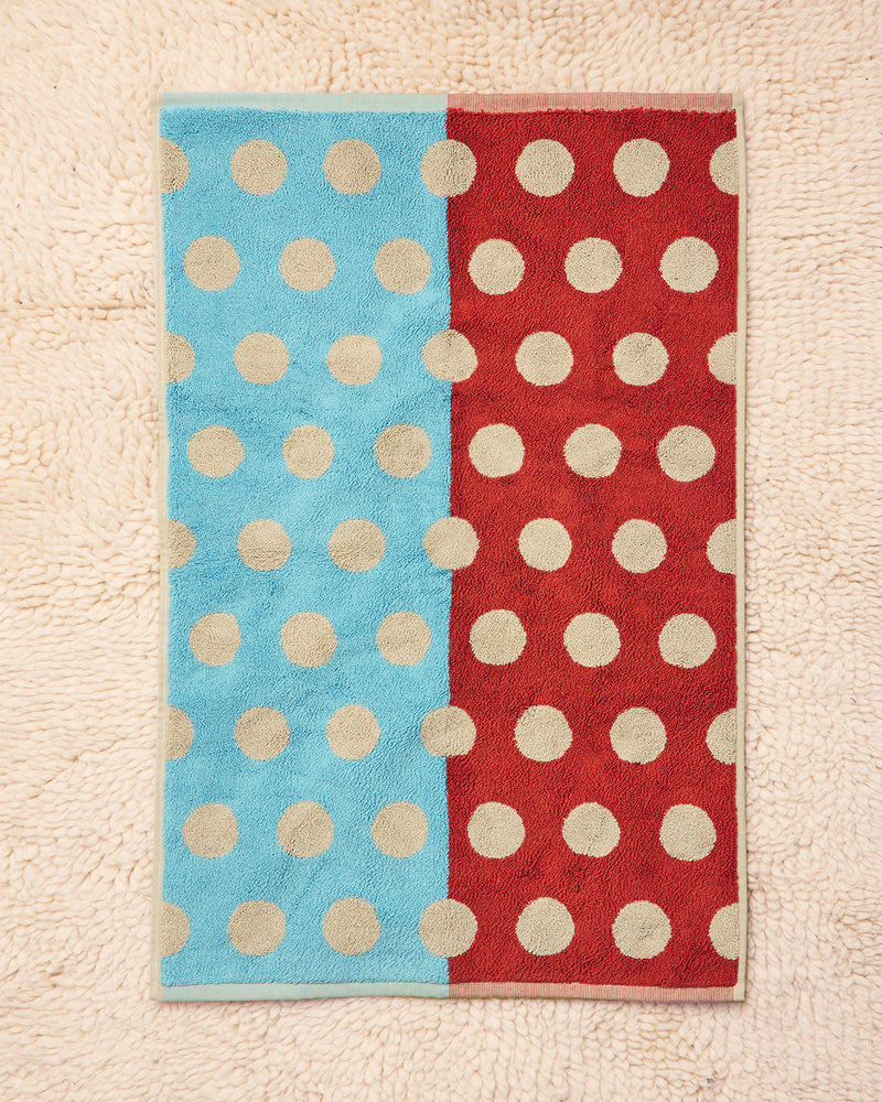 Two polka dot towels, one blue and one red, on a textured surface.