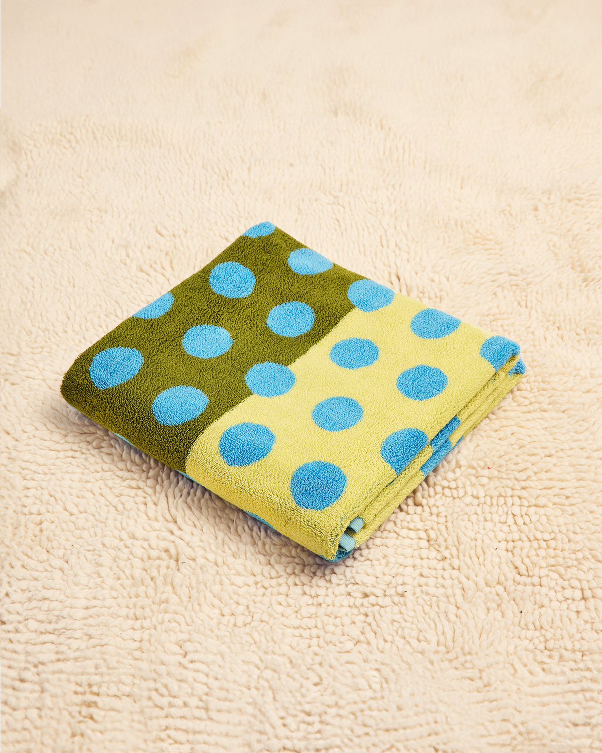 Folded towel with green and yellow pattern on a beige surface 