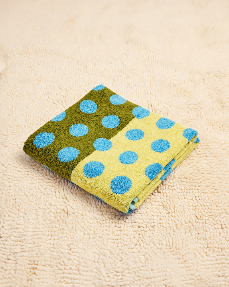 Folded towel with green and yellow pattern on a beige surface 