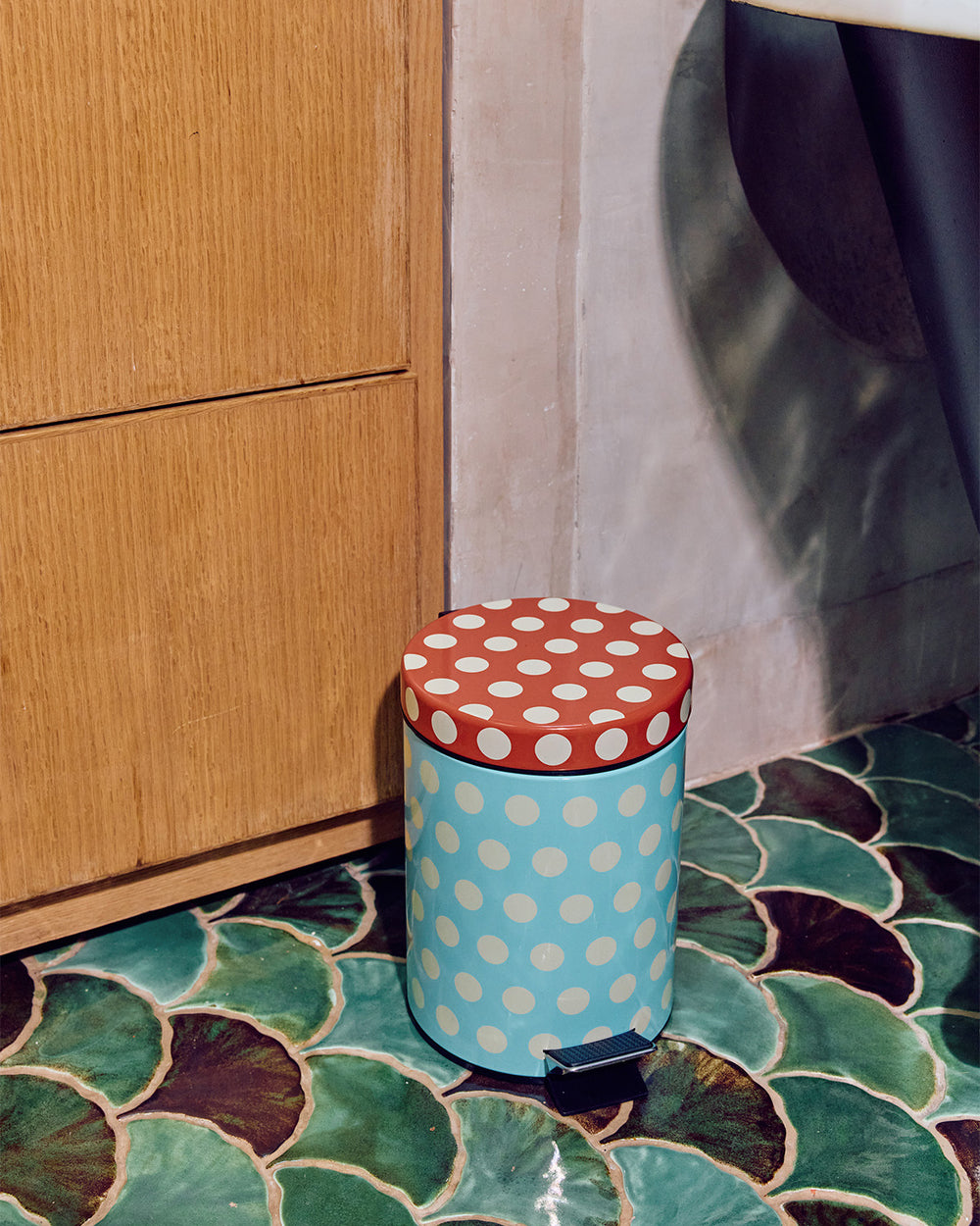 Dot Trash bin in blue and brown on green tile floor 