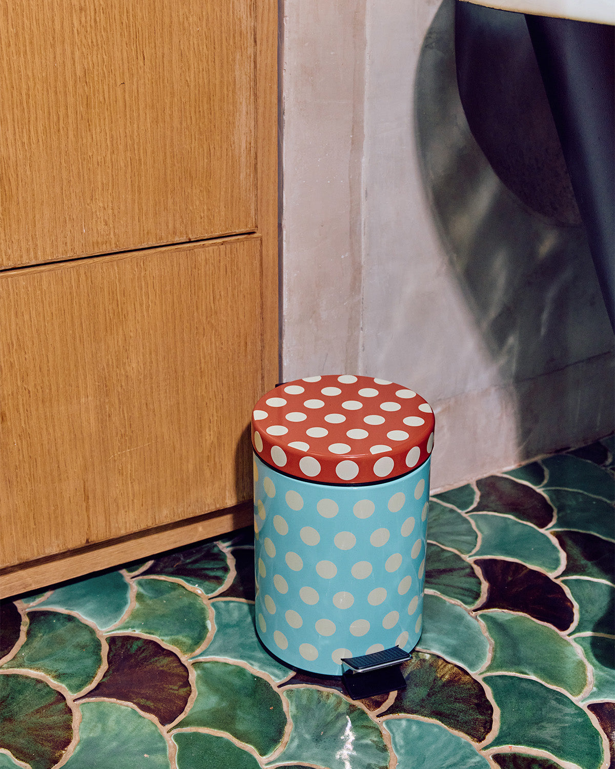 Dot Trash bin in blue and brown on green tile floor 