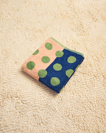 Folded towel with green polka dots on a beige surface 