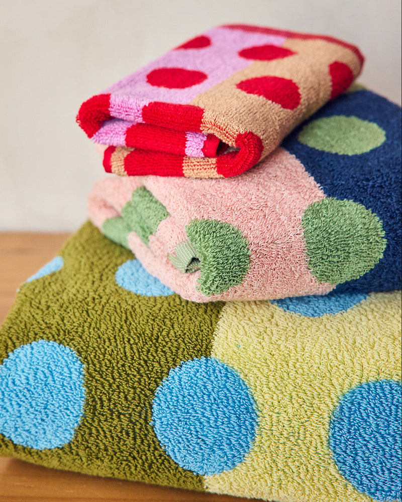 Stack of colorful polka dot towels on a wooden surface with a neutral background 