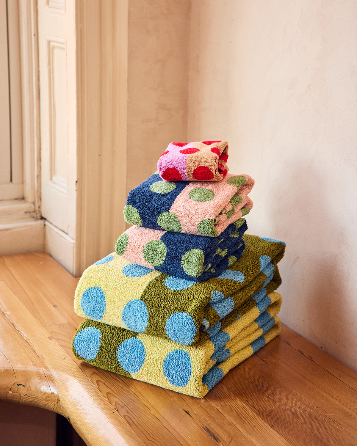Stack of colorful polka dot towels on a wooden surface. 