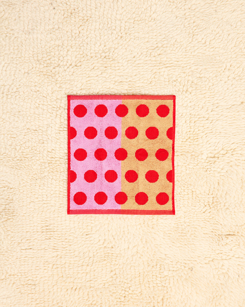Washcloth with red polka dots on a beige background
