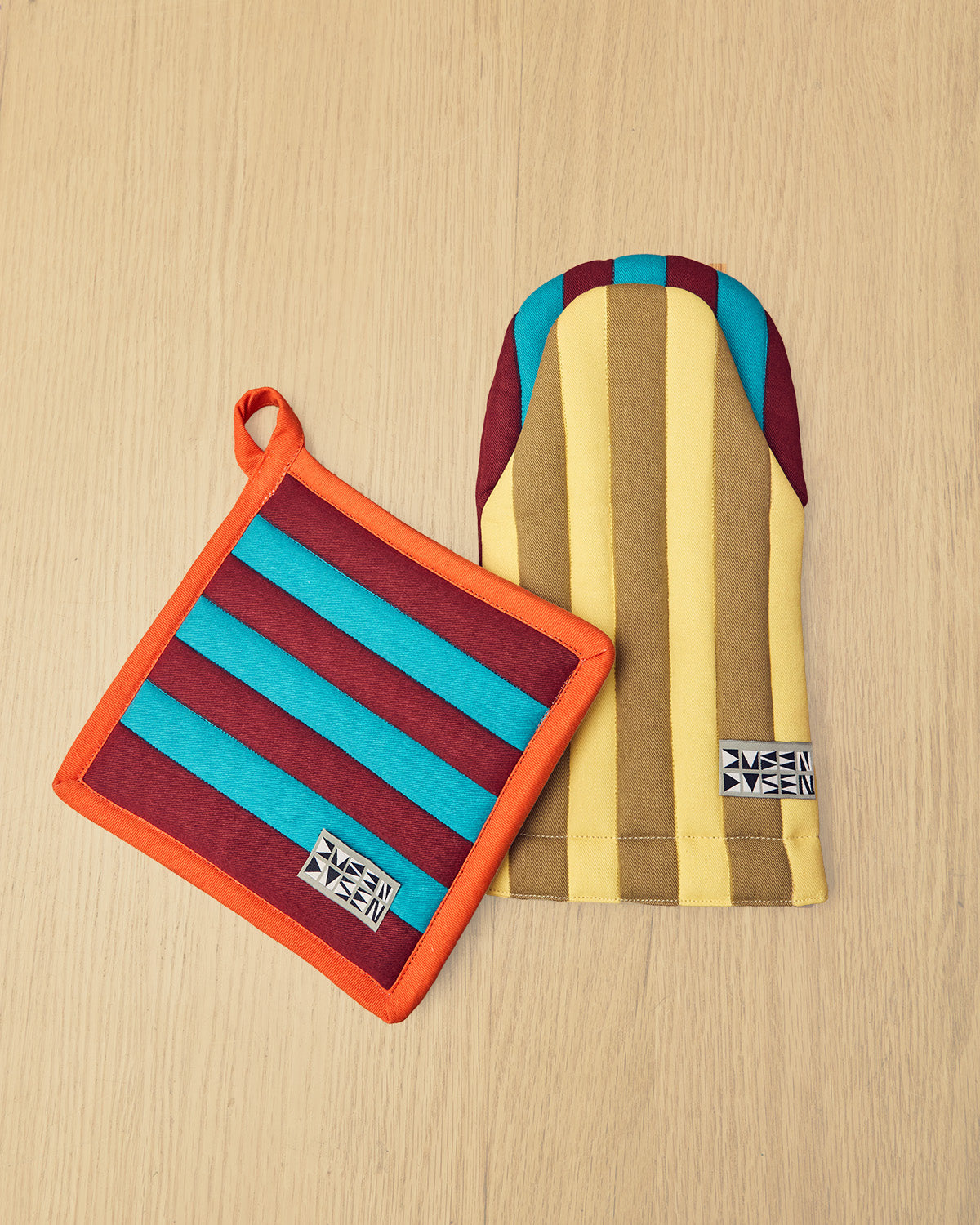 Striped pot holder and oven mitt on a wooden surface