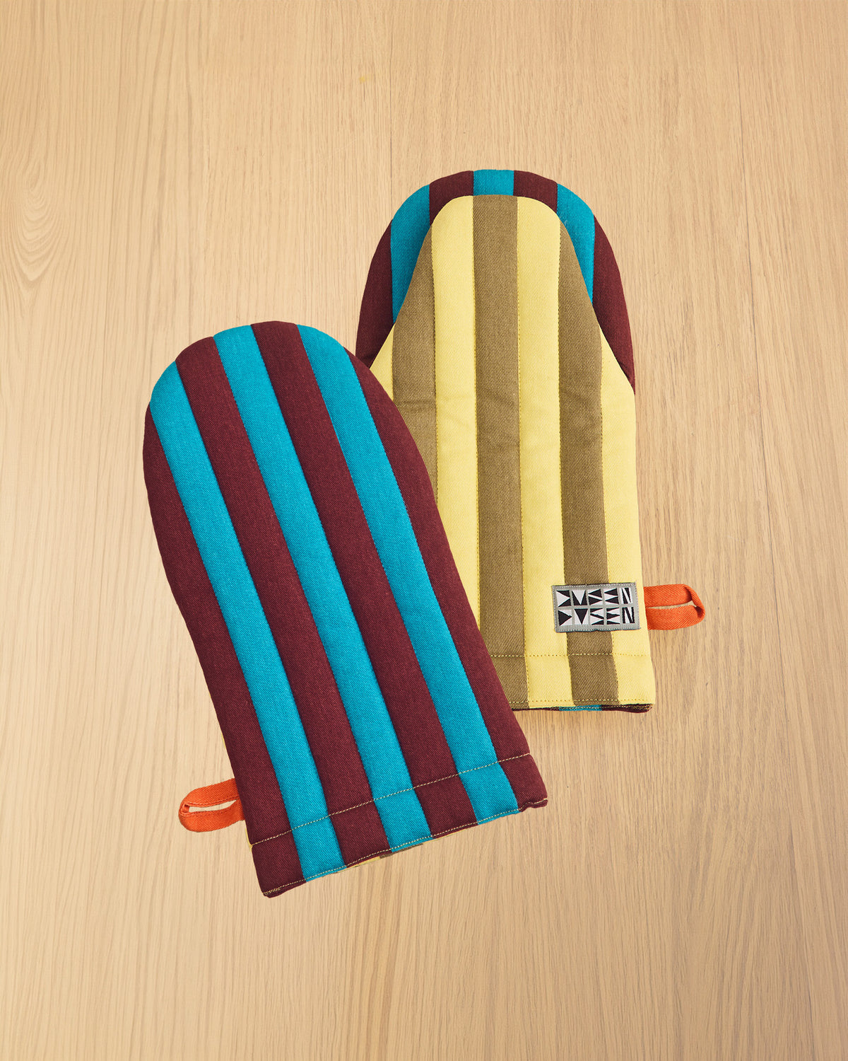 two striped dragonfly oven mitts on wooden table