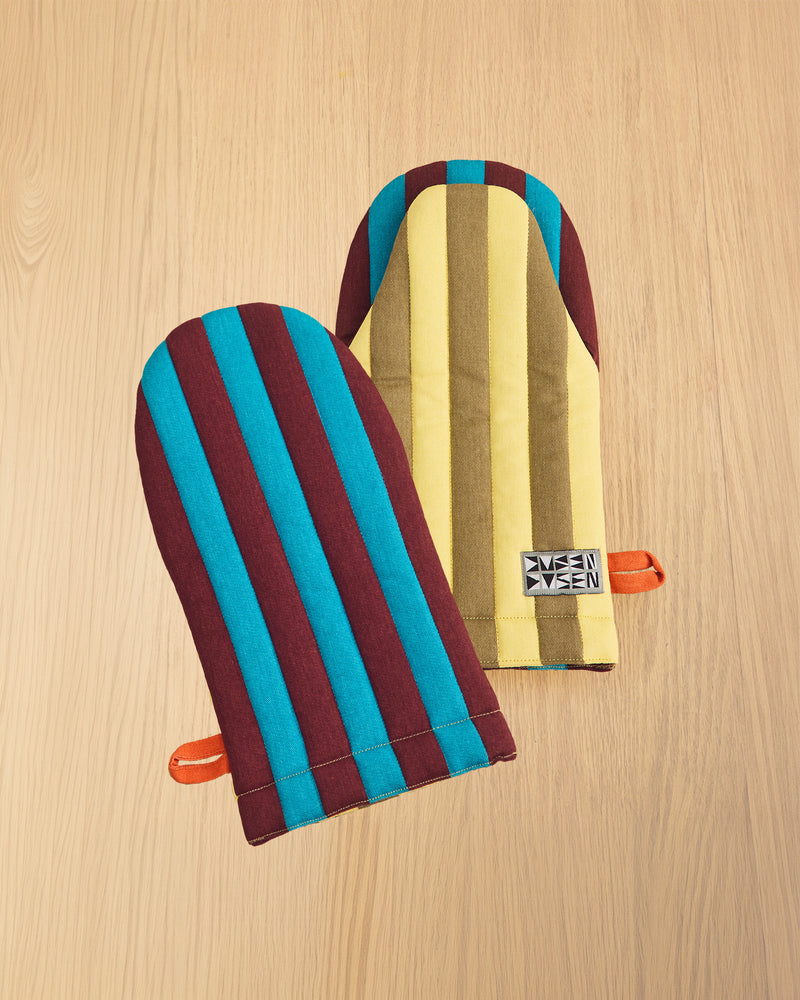 two striped dragonfly oven mitts on wooden table