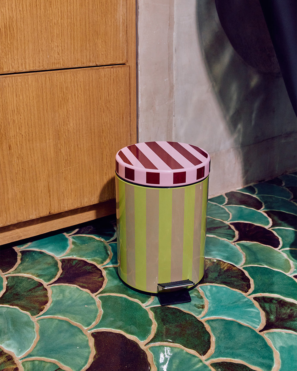 Colorful striped trash can on a patterned floor