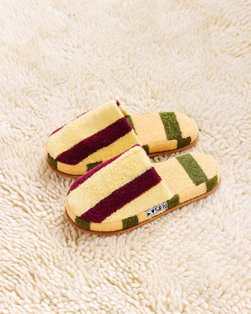 Pair of yellow Ginkgo slippers on a white rug