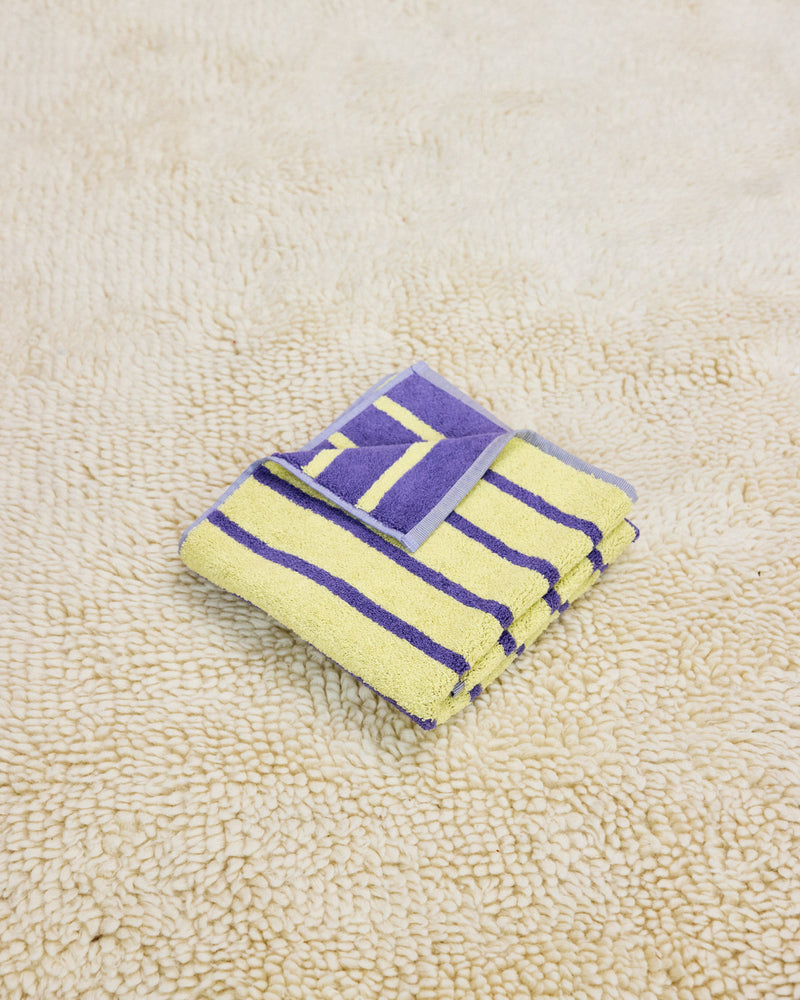 yellow and purple striped towel folded on rug
