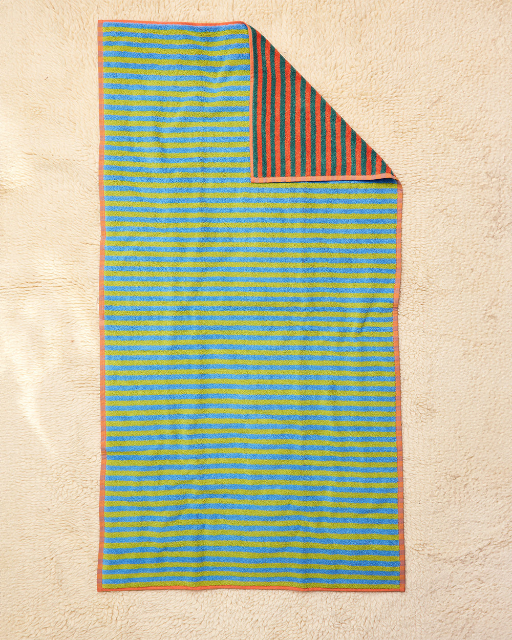 Striped towel with blue and green pattern on a beige surface