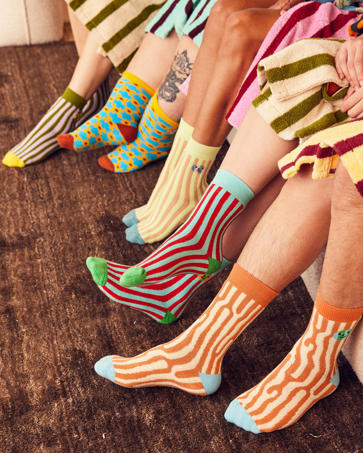 five people wearing socks on a couch with brown carpet