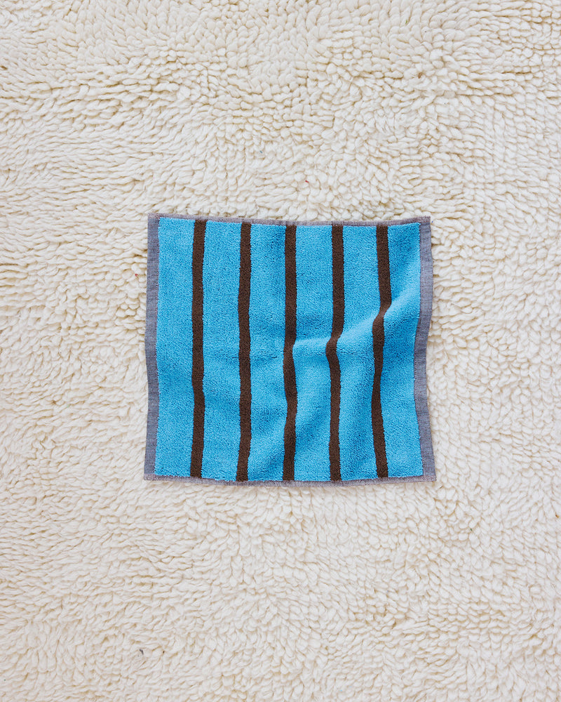 Blue and brown stripe washcloth on rug 