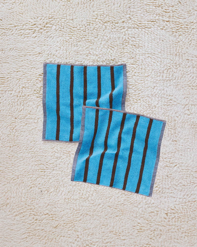 Two heron washcloths on a beige carpet 