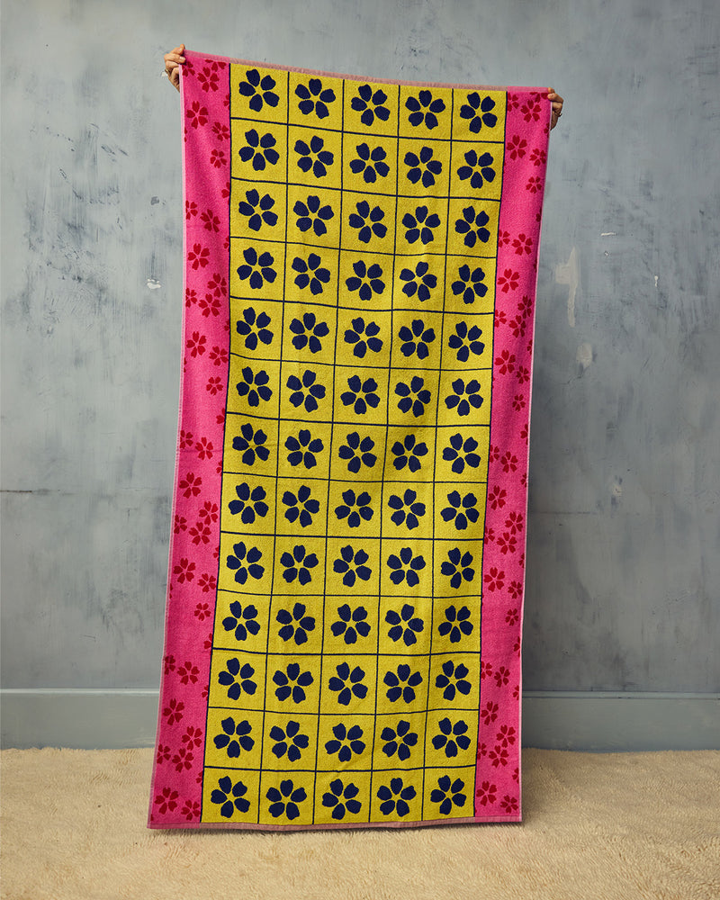 Colorful towel with floral pattern held against a gray wall