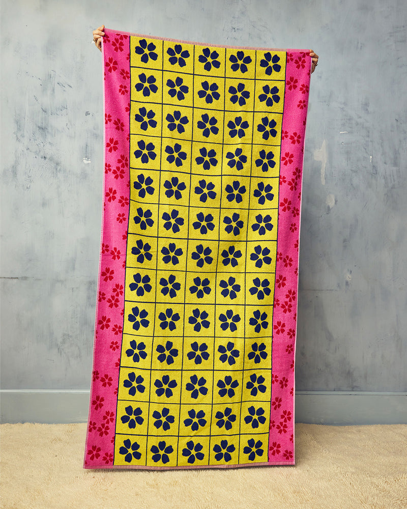 Colorful towel with floral pattern held against a gray wall