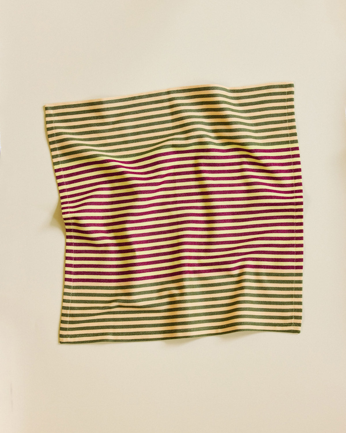 Striped fabric with green and red pattern on a beige background