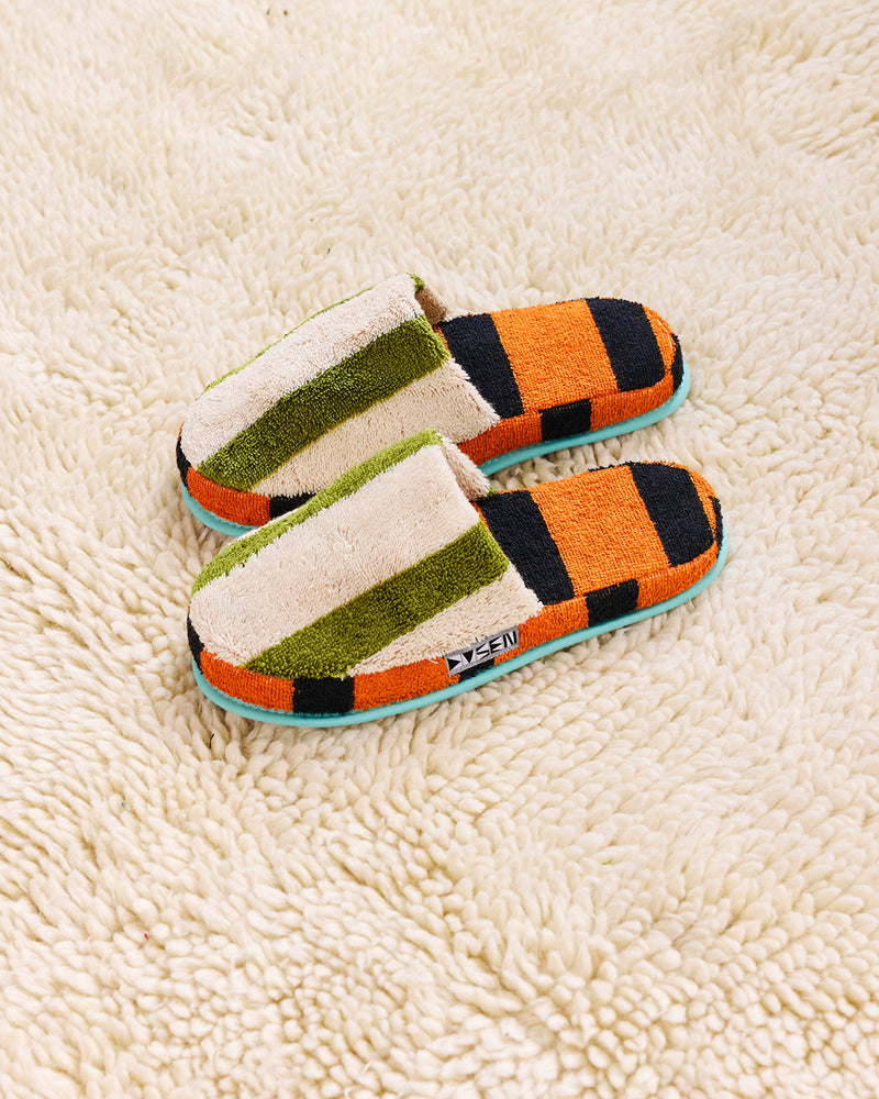 green and white slippers with orange and black sole on cream carpet