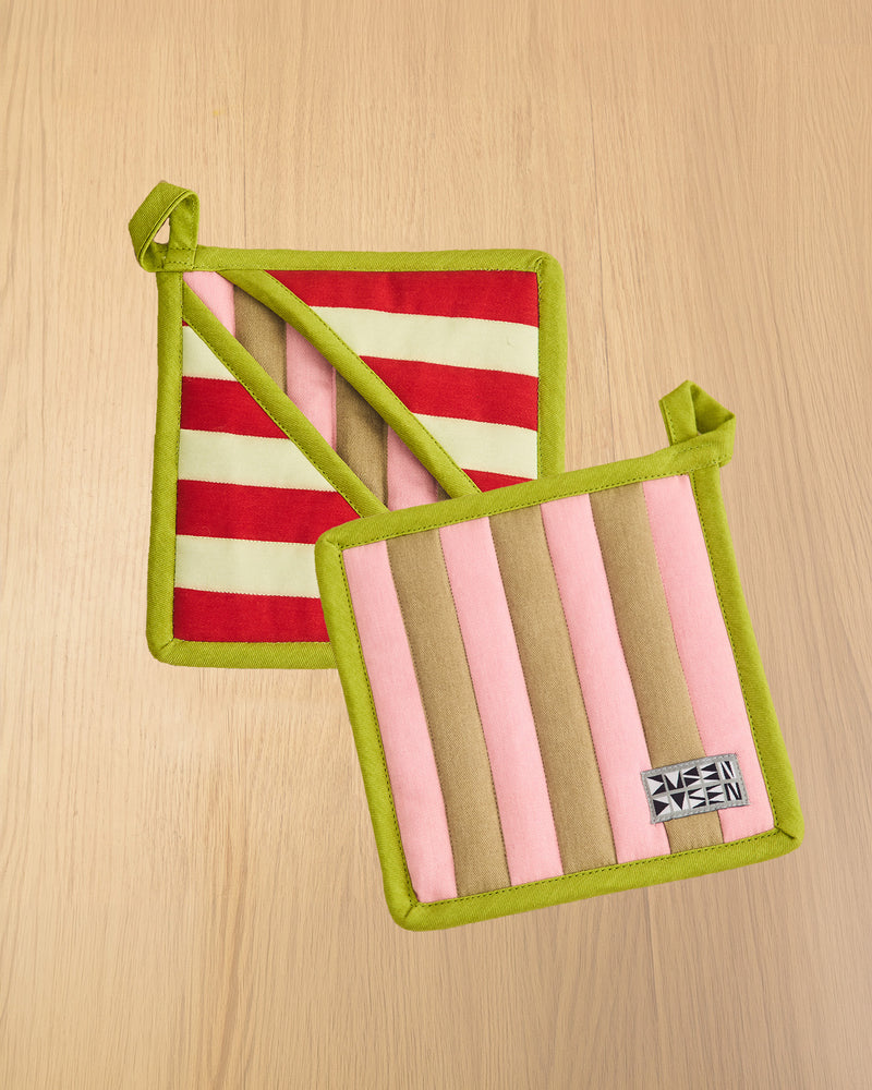 Two striped pot holders with green edges on a wooden surface