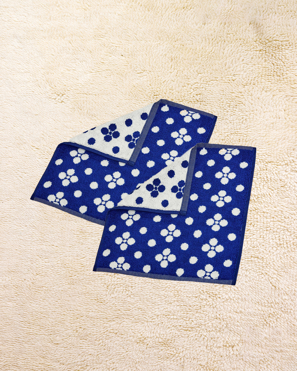 Two Lisa Washcloths on a beige carpet