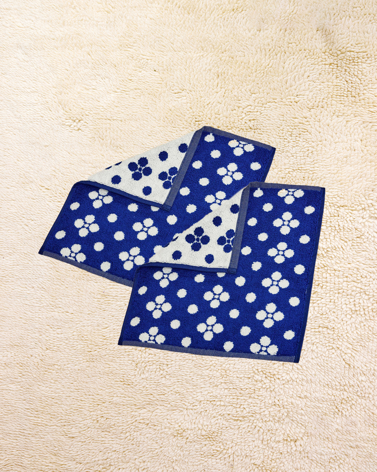 Two Lisa Washcloths on a beige carpet