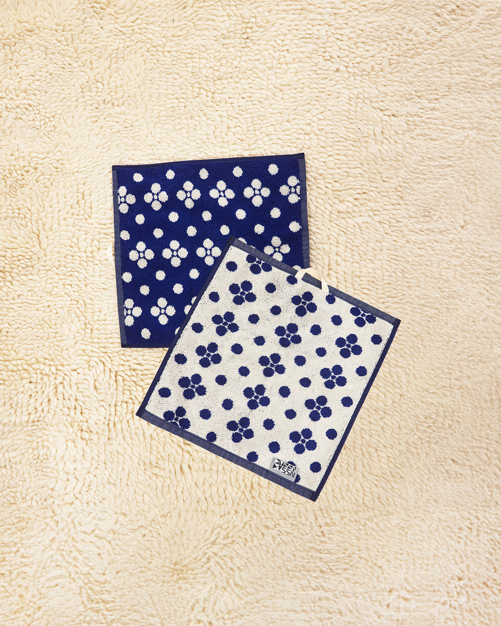 Two Lisa Washcloths on a beige carpet