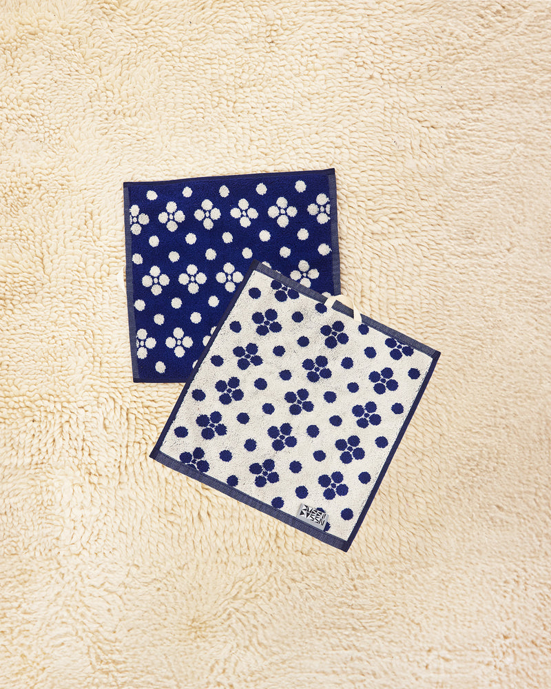 Two Lisa Washcloths on a beige carpet