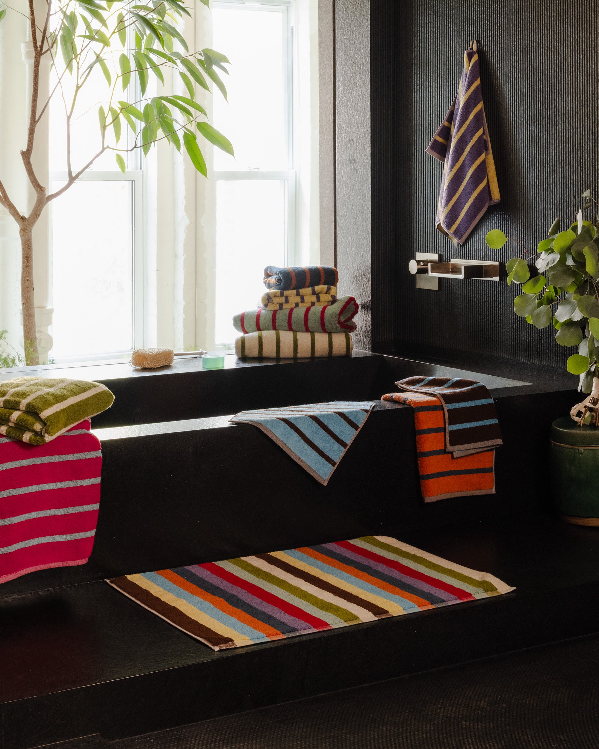black stone bathroom with Hummingbird bath mat at the foot of tub ; Small but mighty