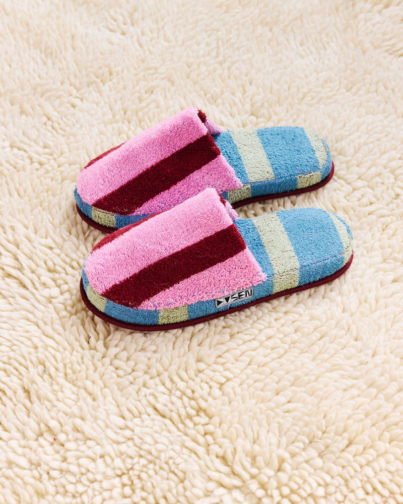 Pair of pink and blue striped slippers on a beige carpet