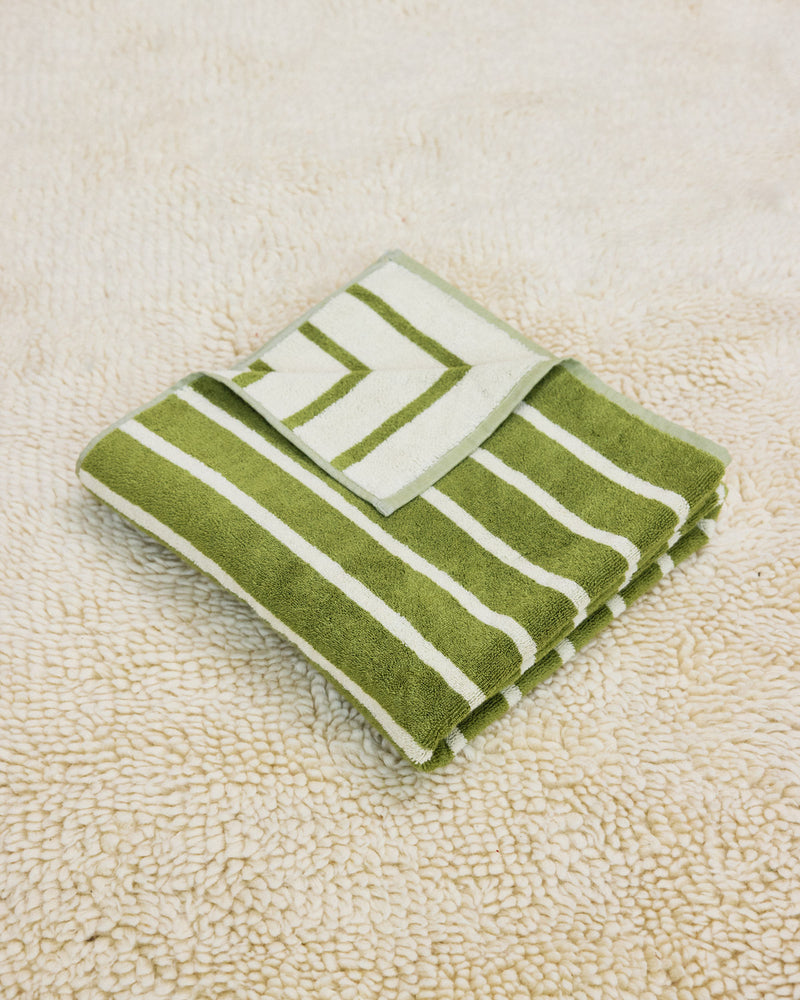 Green and white striped towel folded on a rug