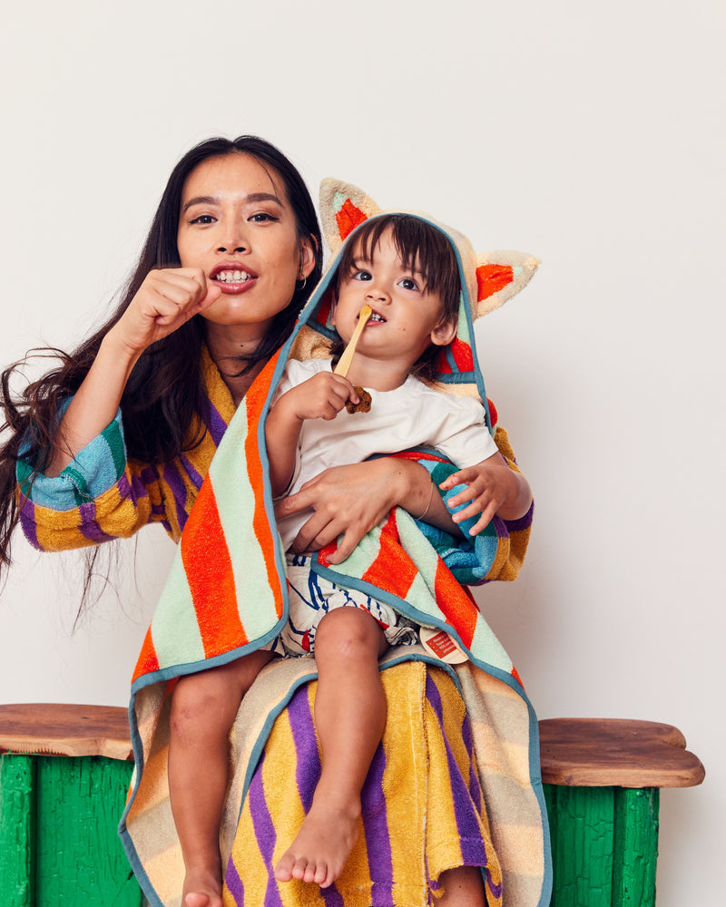 Mona hooded towel on child who is brushing teeth in mothers lap 
