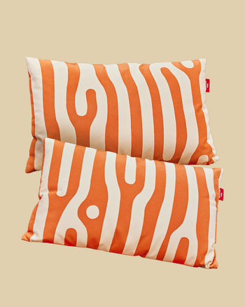 Two orange and white patterned pillows on a beige background 