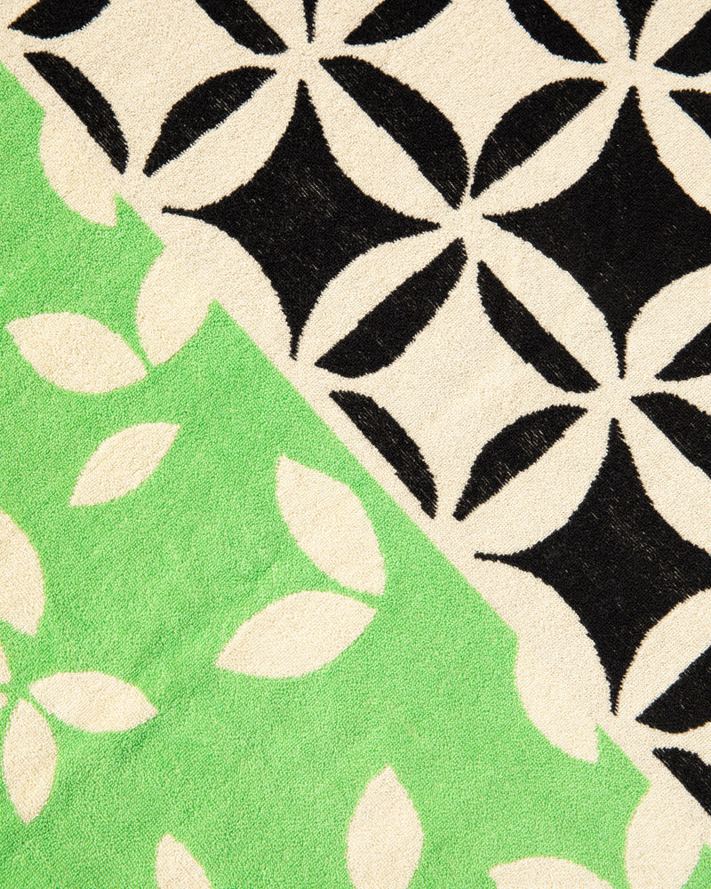 Close-up of fabric with black and white geometric pattern and green and white floral pattern.