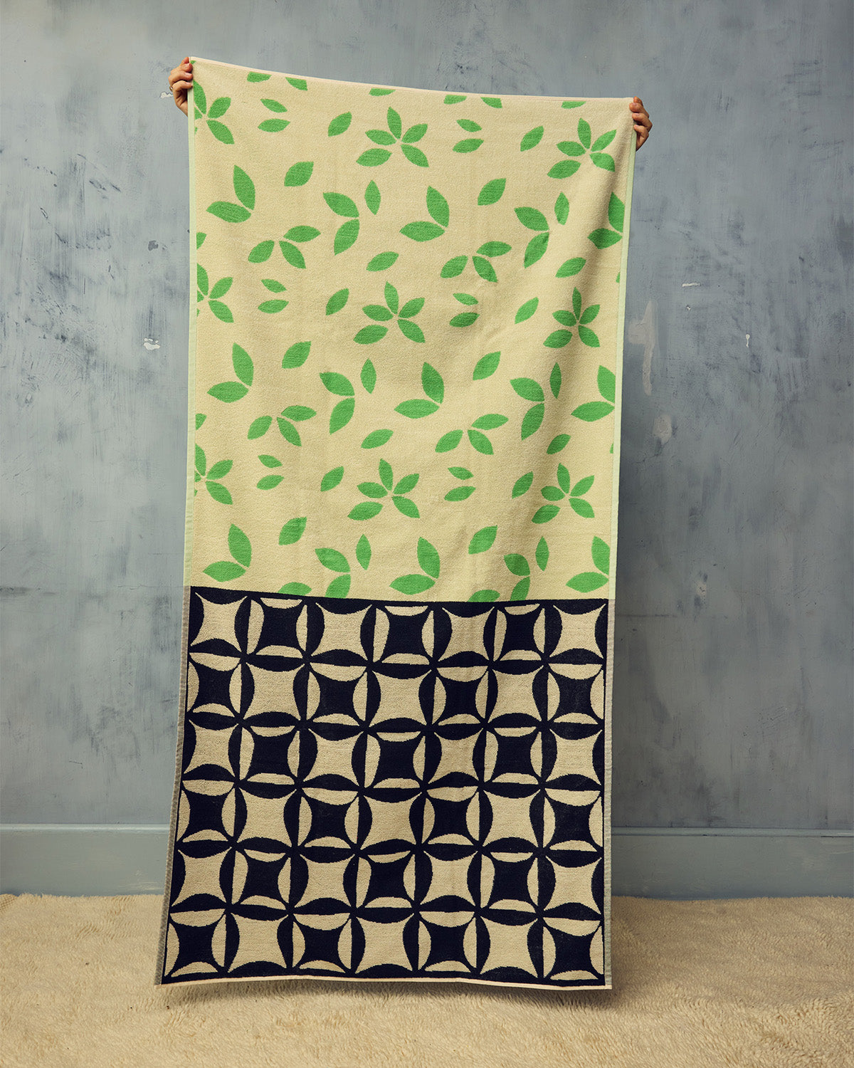 Towel with green leaf pattern on beige background and black geometric pattern on navy background