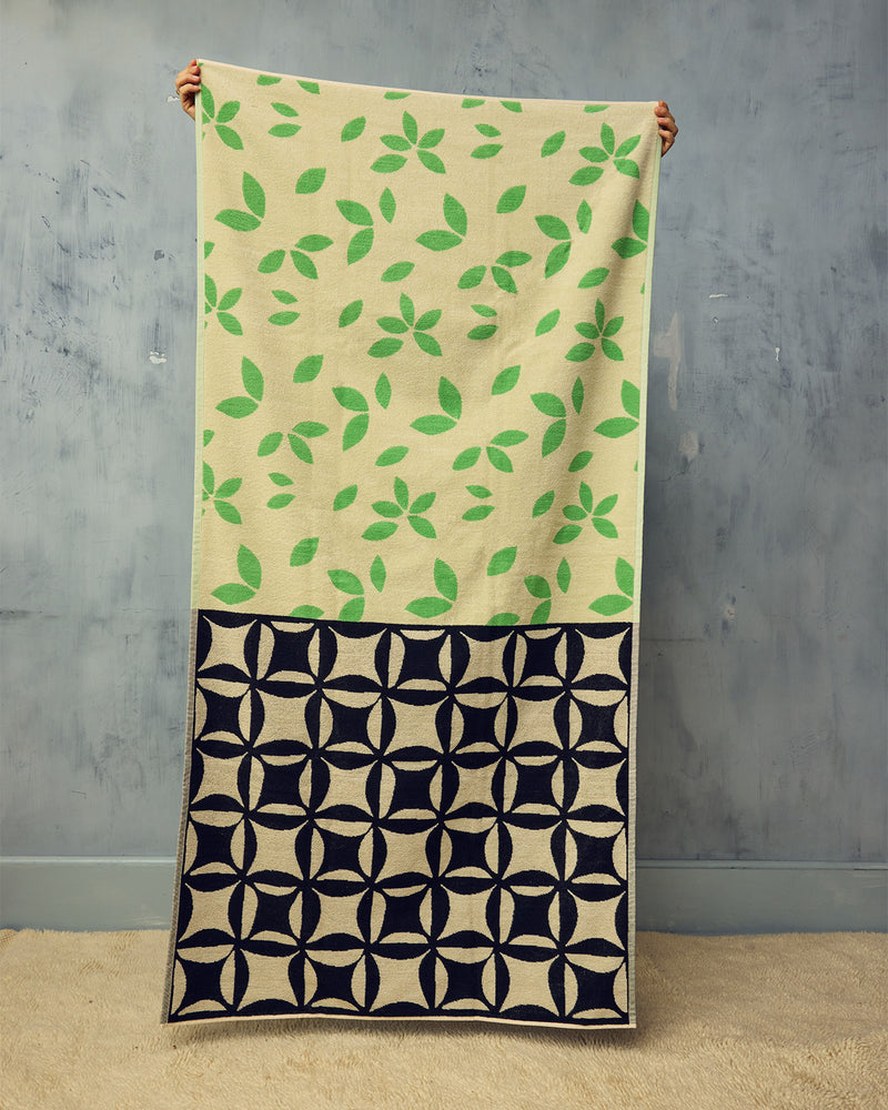 Towel with green leaf pattern on beige background and black geometric pattern on navy background