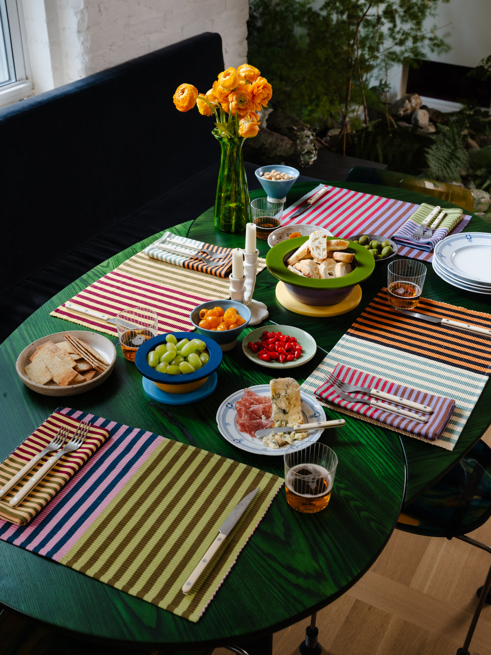 Set of four striped placemats on a green table with full spread of food