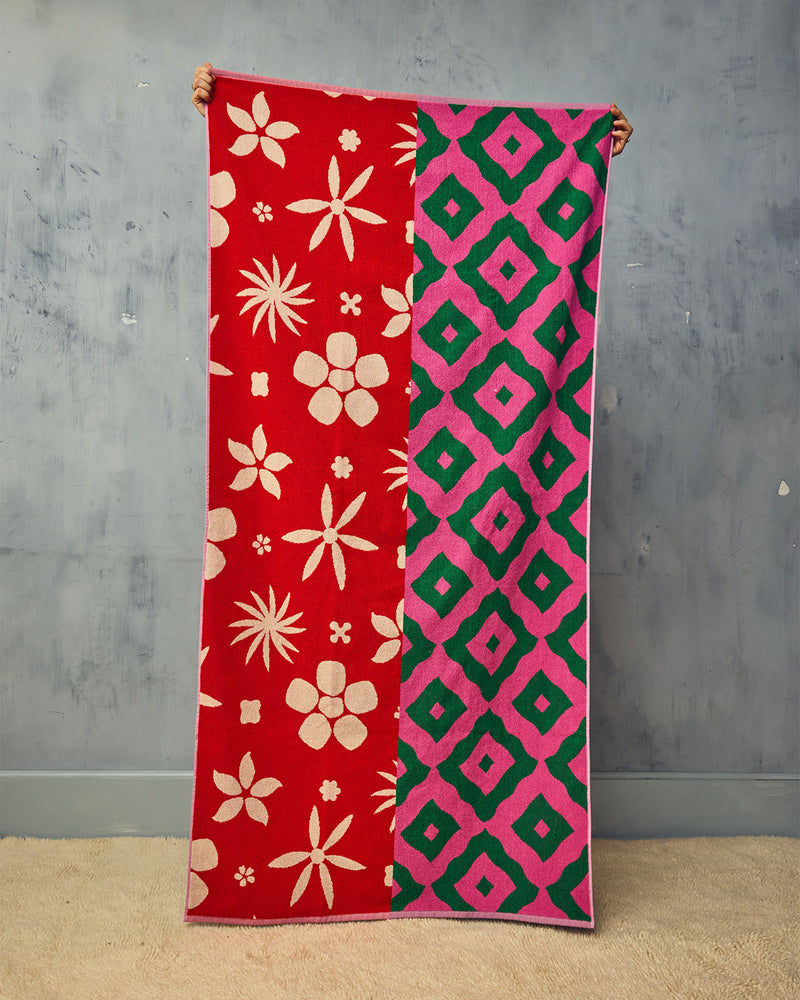 Peony towel being held up in front of plain plaster wall