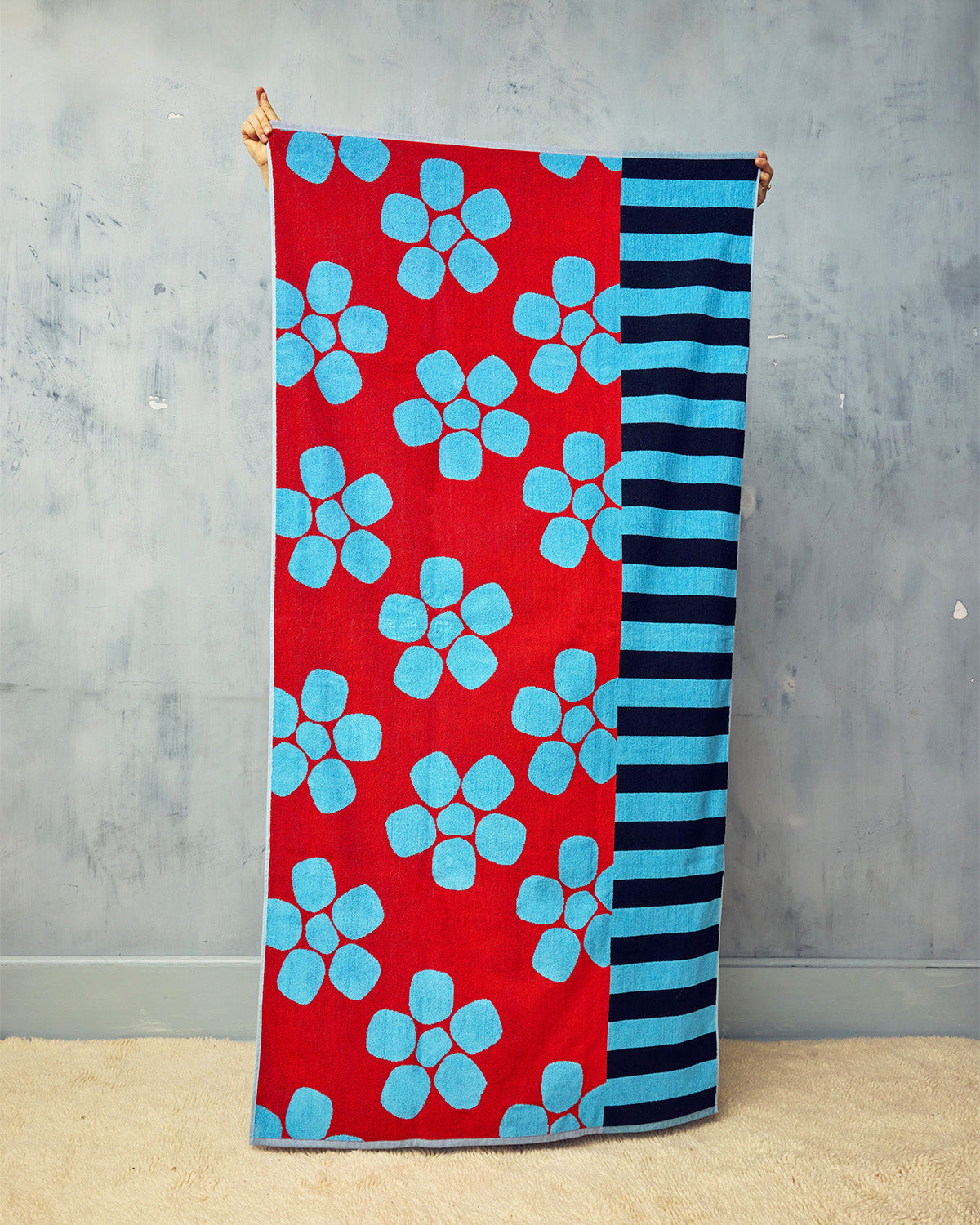 Towel with red background and blue floral pattern on a gray background