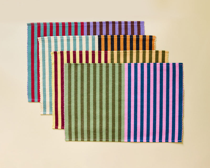 Set of four striped placemats on a beige background