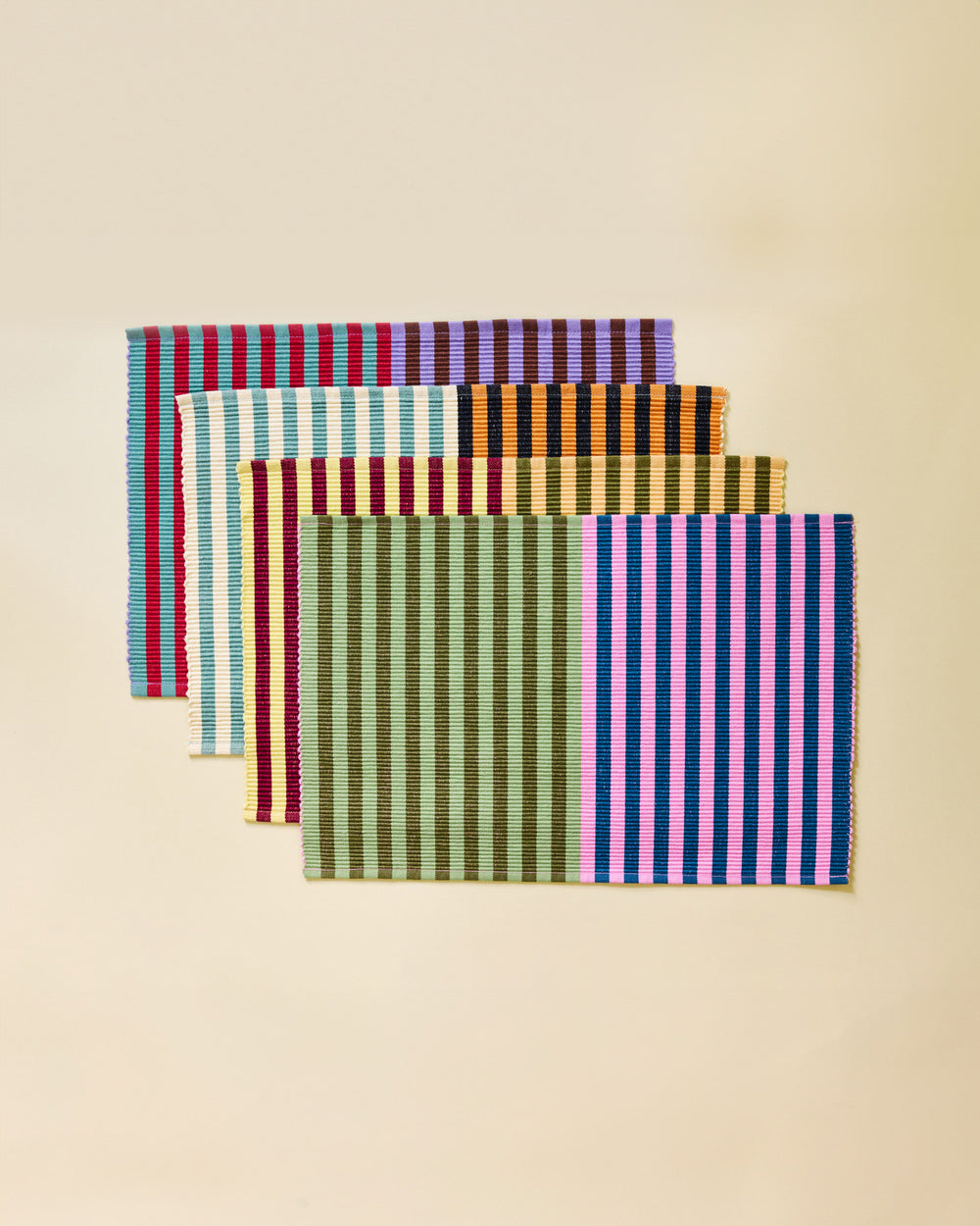 Set of four striped placemats on a beige background