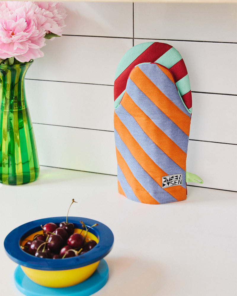 Pumpernickel oven mitt on kitchen counter with a bowl of cherries 