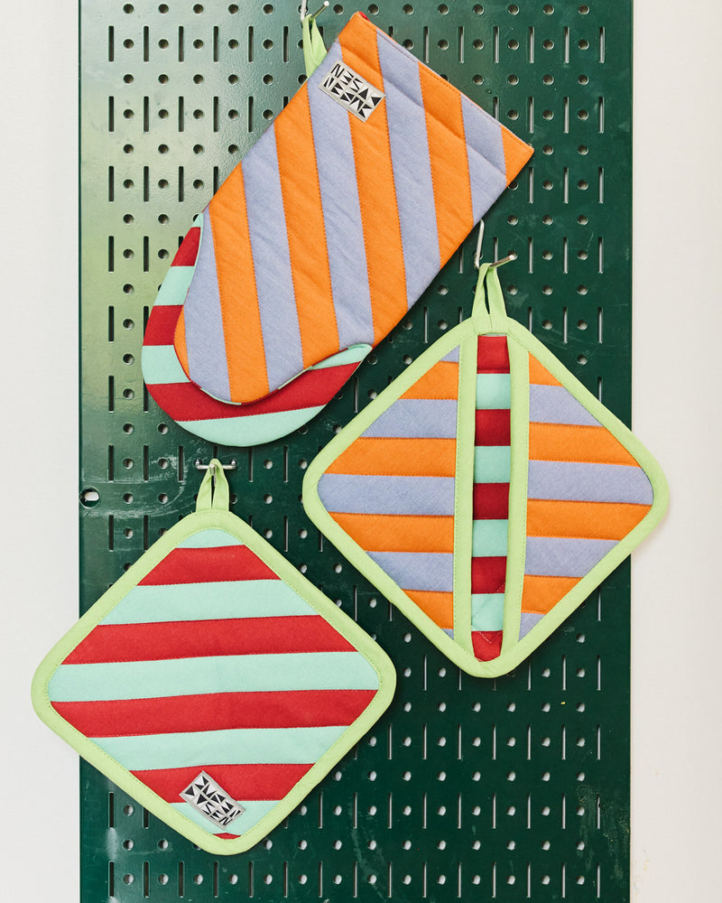 pumpernickel oven mitt and two pot holders on a green hanging board