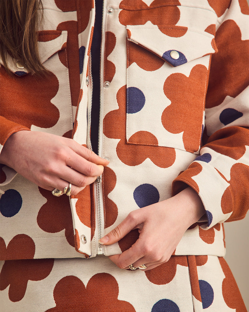 Person wearing a coat with a floral pattern, focusing on the zipper area.