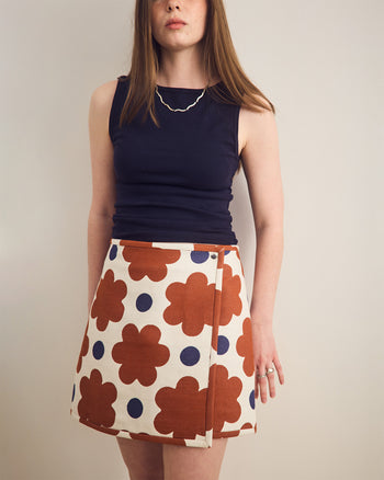 ["Woman wearing a navy top and a patterned skirt with flowers and polka dots on a plain background", " Picked from the brambles in Skirt Land <br> <br> Erin is 5'8\" and wears a size M"]