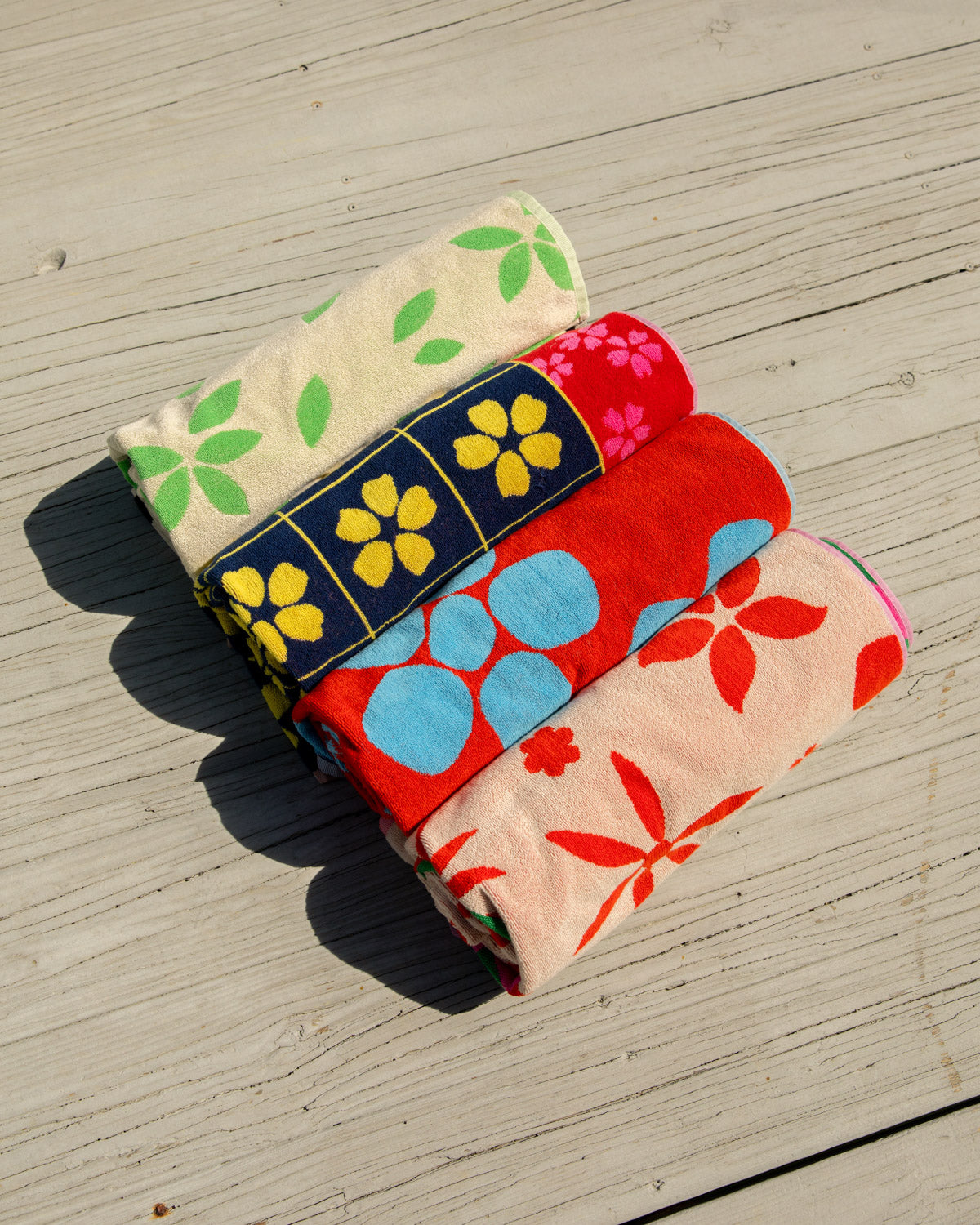 4 rolled up beach towels on a wooden dock
