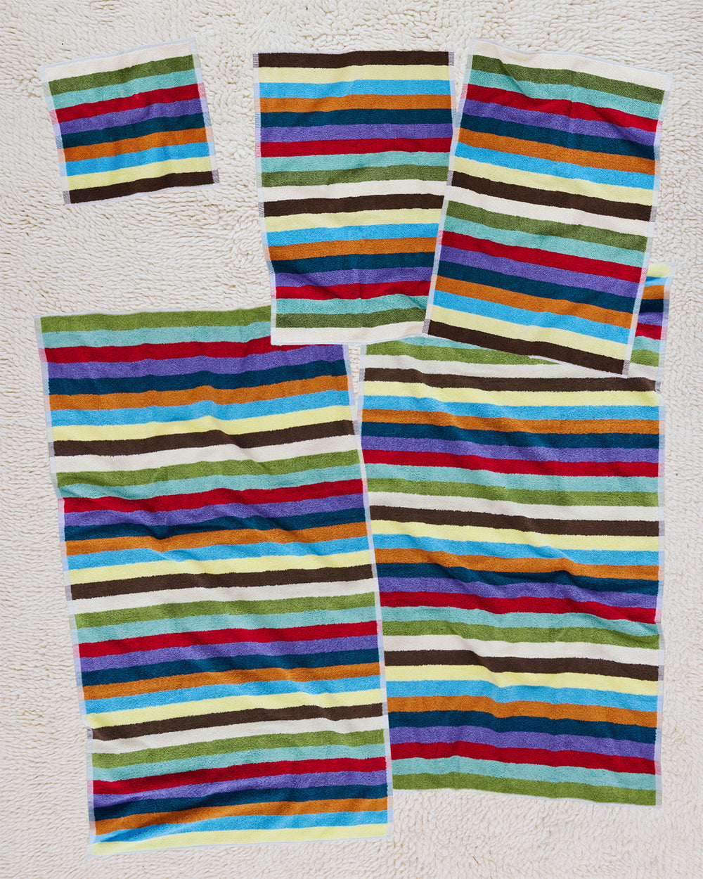 Set of 5 colorful striped towels on a white background